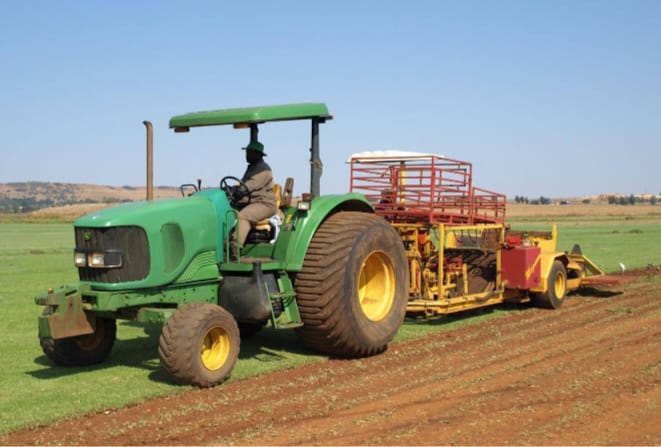 Green tractor preparing soil beds for new turf planting